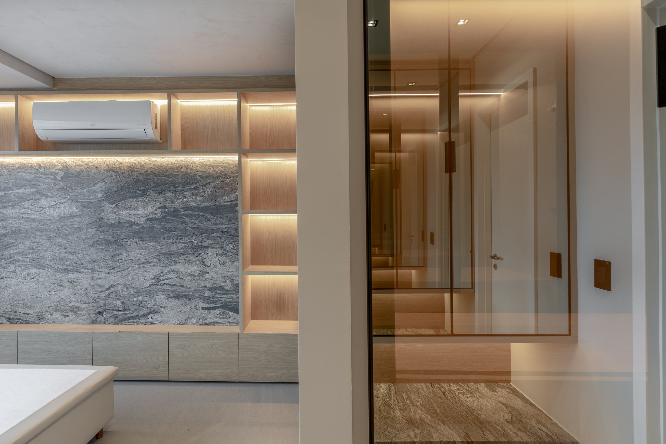 Apartamento Dr. Melo Alves com painel iluminado, pedra cinza e marcenaria clara.