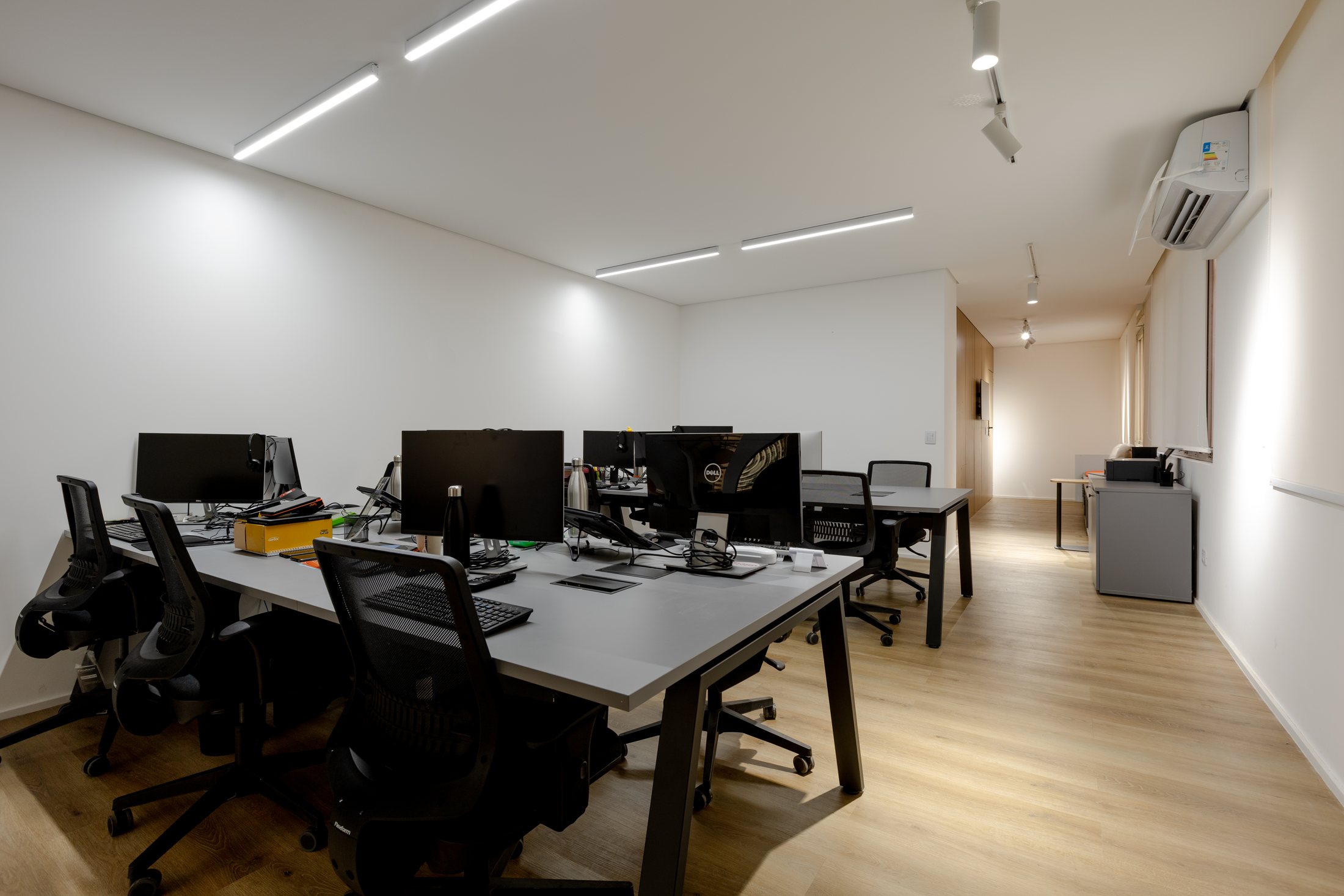 Escritório Valetti com mesas de trabalho, iluminação linear e layout funcional.
